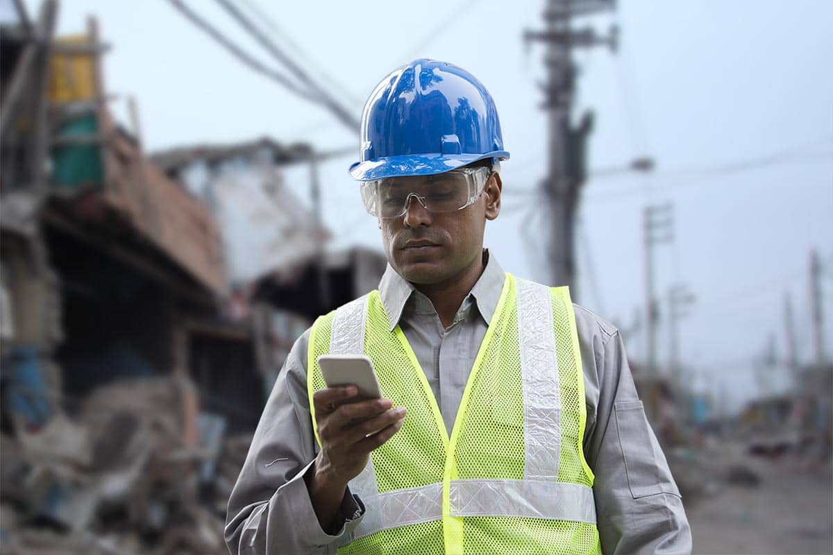 man looking at phone app in natural disaster zone