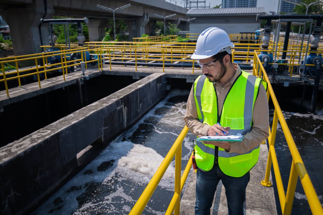 Male engineer using a tablet device while performing an environmental inspection in a water treatment facility.