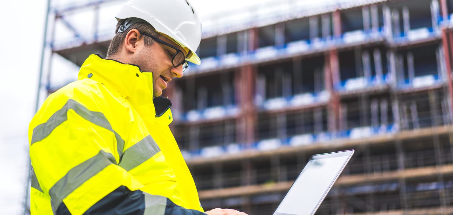 A male field service manager using a laptop to access CMMS software for asset maintenance.