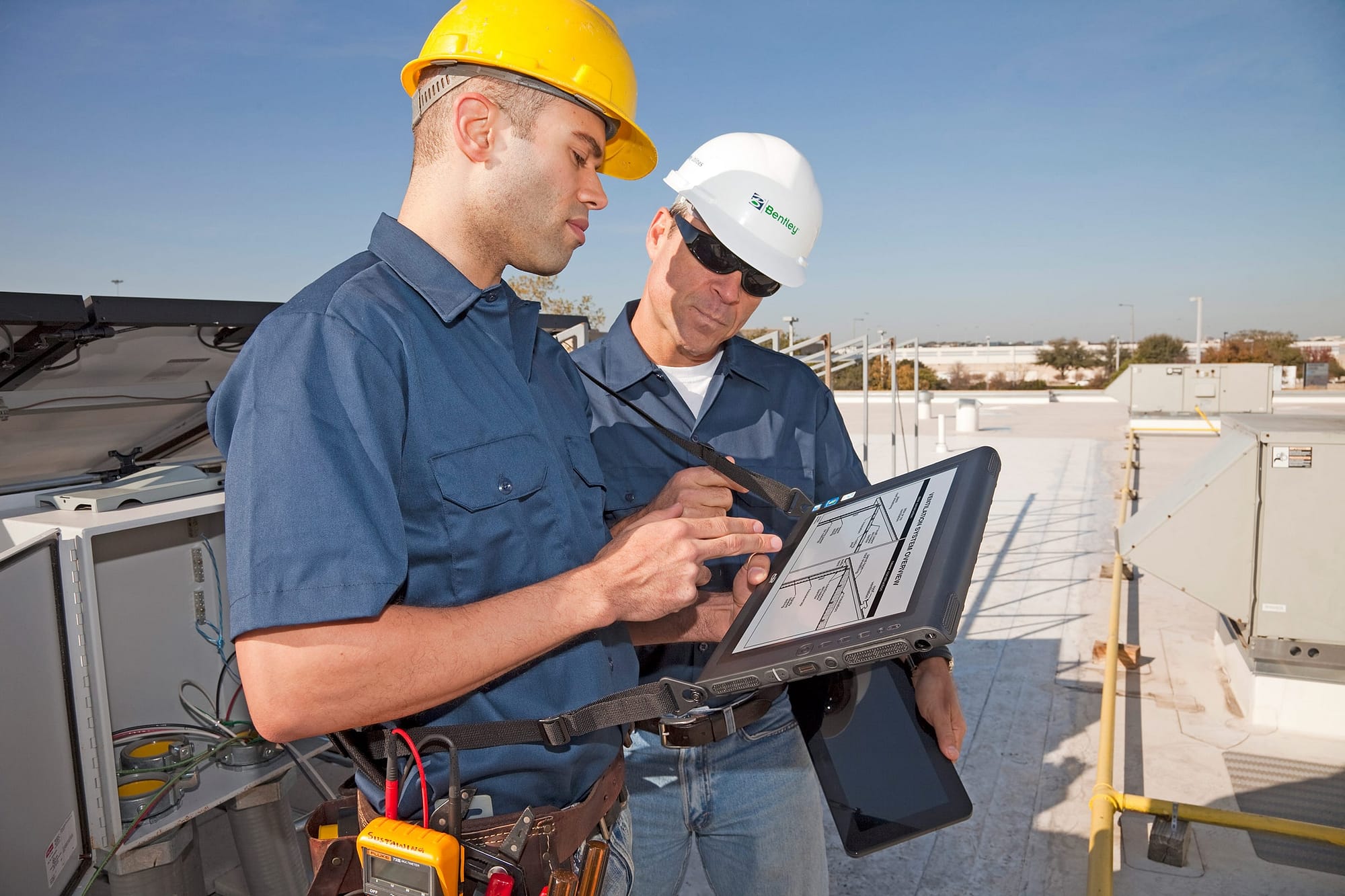 Two men inspecting HVAC with field service management app on tablet