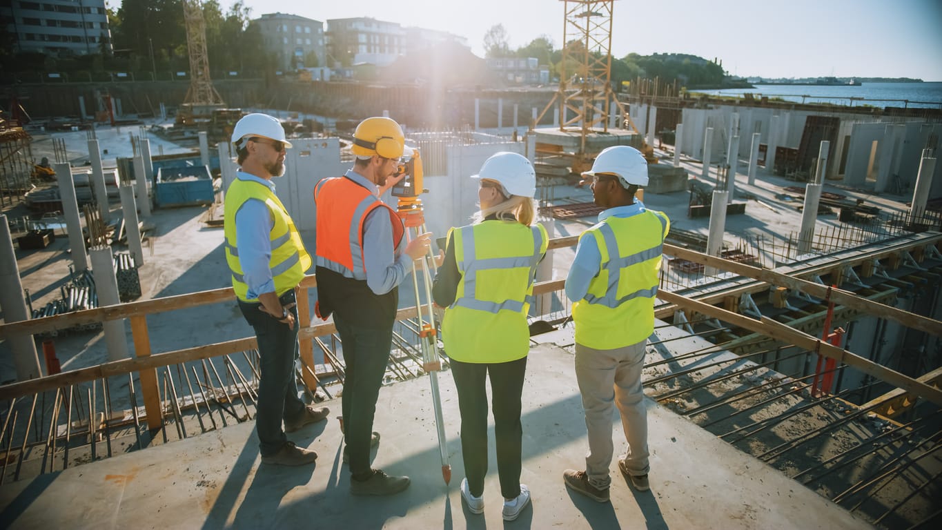 Benefits of job management software - Team of field service professionals in a construction site discussing project plans.