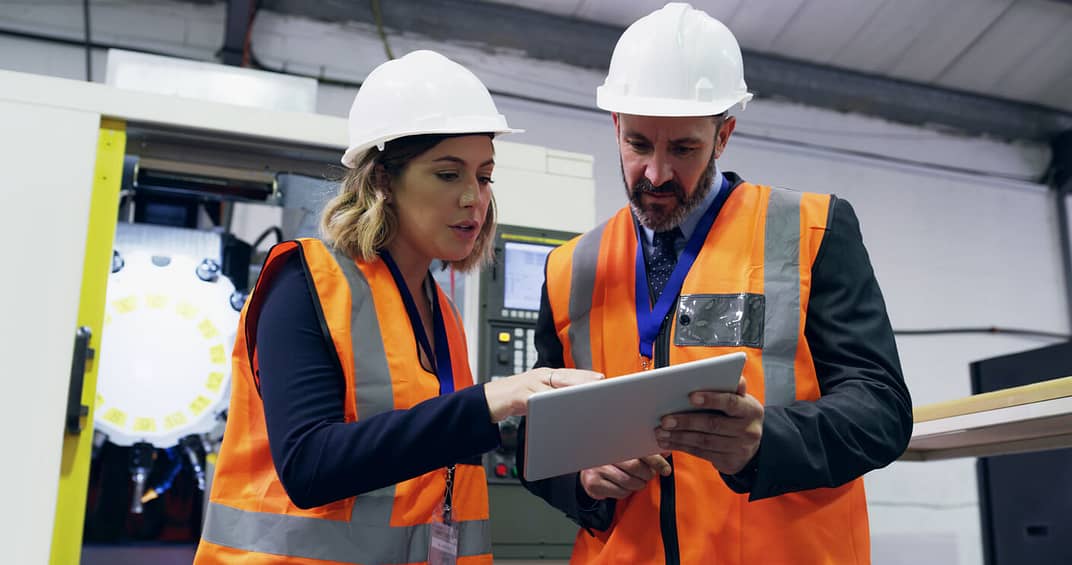 man and woman looking at tablet assessing equipment report and analytics