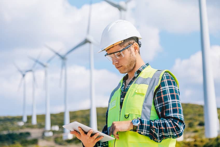 man looking at tablet servicing wind farm